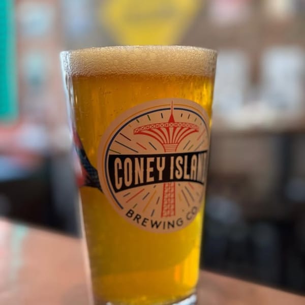 A glass of golden beer with a foamy head and a "Coney Island Brewing Co" label.