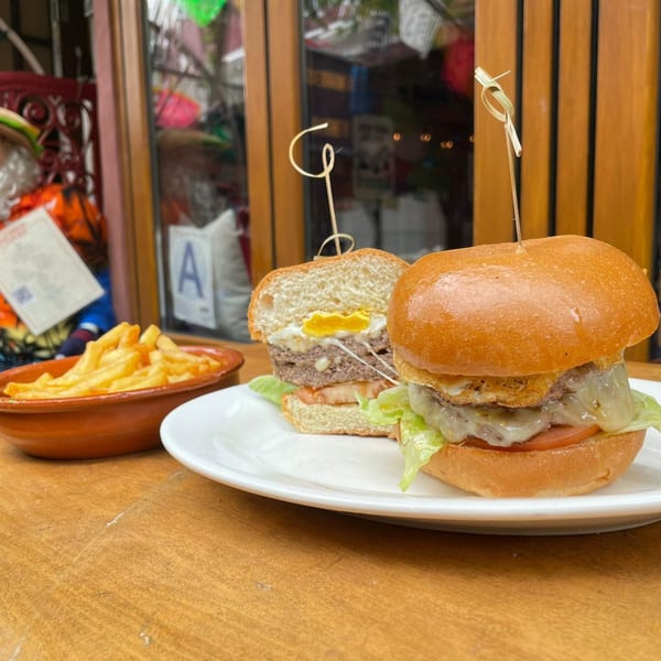 Two Burgers and Beer burgers, one cut in half revealing a fried egg, with a side of fries.